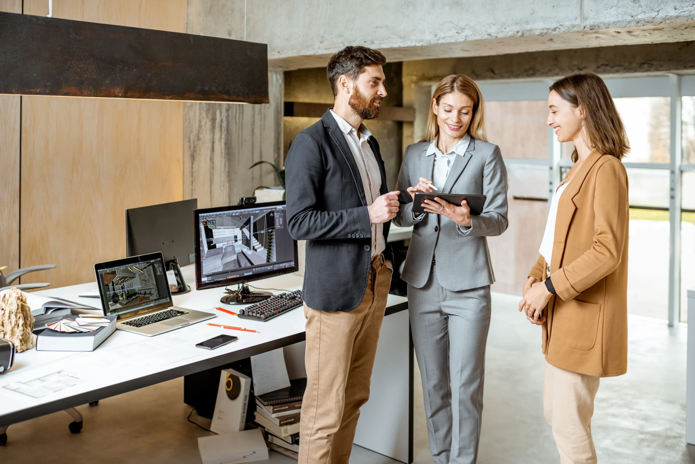 Drei Personen stehen in einem Büro und unterhalten sich