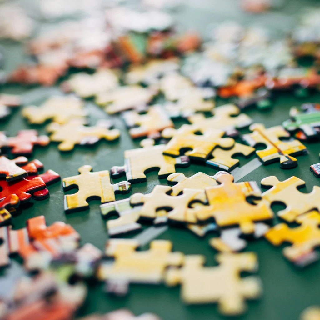 Viele bunte Puzzleteile die auf einem Tisch verstreut liegen